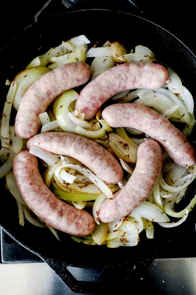 bratwurst in onions in pan | foodiecrush.com