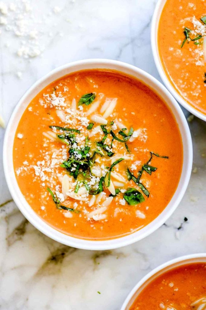 bowl of tomato basil soup garnished with Parmesan and fresh basil