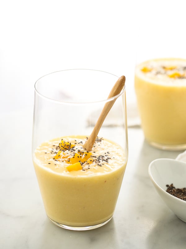 mango smoothie in glass with wooden spoon