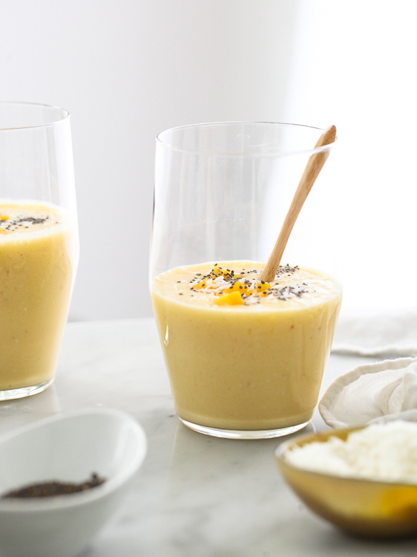 mango smoothie in glass garnished with mango chunks and chia seeds