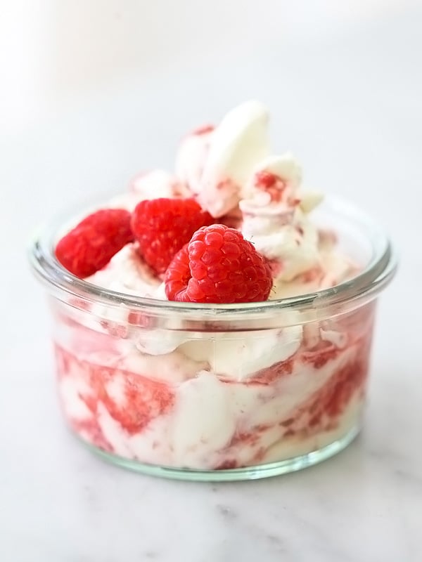 raspberries and cream in small glass jar