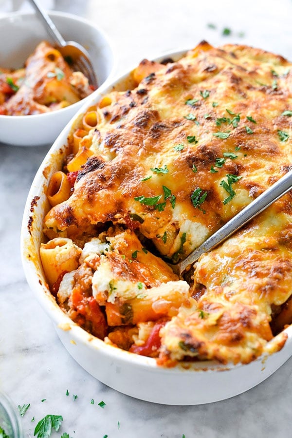 cheesy baked rigatoni in white casserole dish with spoon