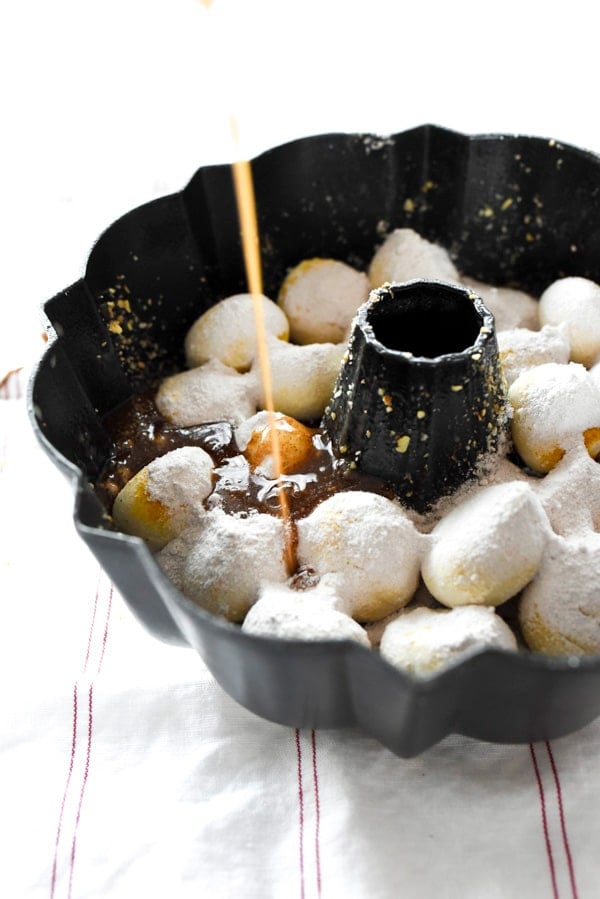 pouring melted butter over uncooked cinnamon monkey bread 