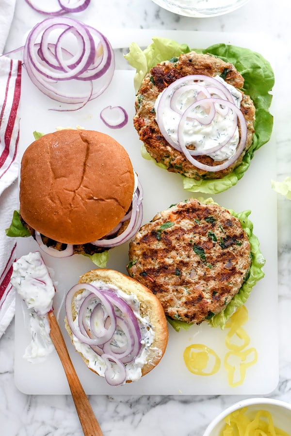 Greek Turkey Burgers with Tzatziki Sauce are packed with fresh spinach, sun-dried tomatoes, oregano and feta cheese for a healthy Mediterranean version for hamburger fans | foodiecrush.com