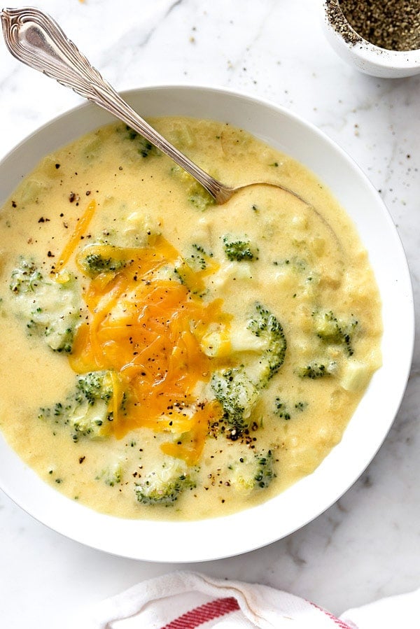cheesy broccoli potato soup in white bowl with spoon