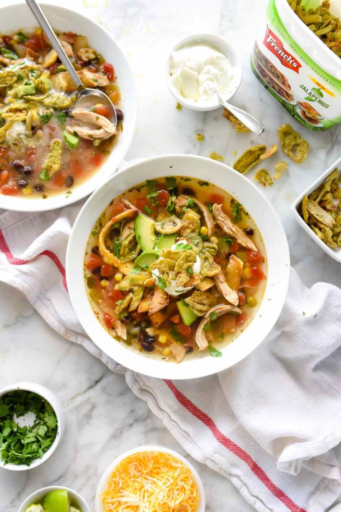 two bowls of chicken tortilla soup surrounded by toppings