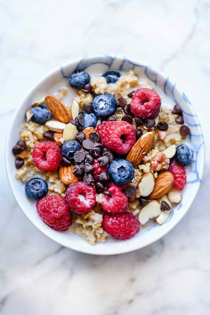 bowl of oatmeal topped with berries, nuts, and chocolate chips