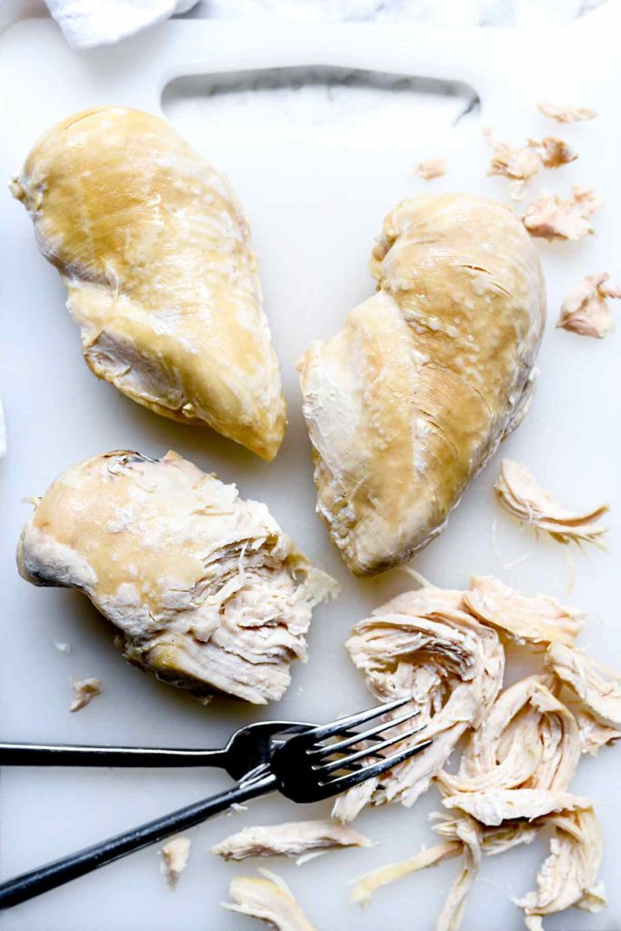 three instant pot chicken breasts on countertop with two forks