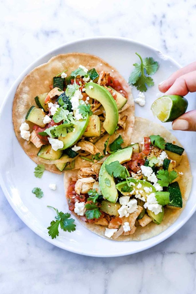 squeezing fresh lime juice onto shredded chicken tacos