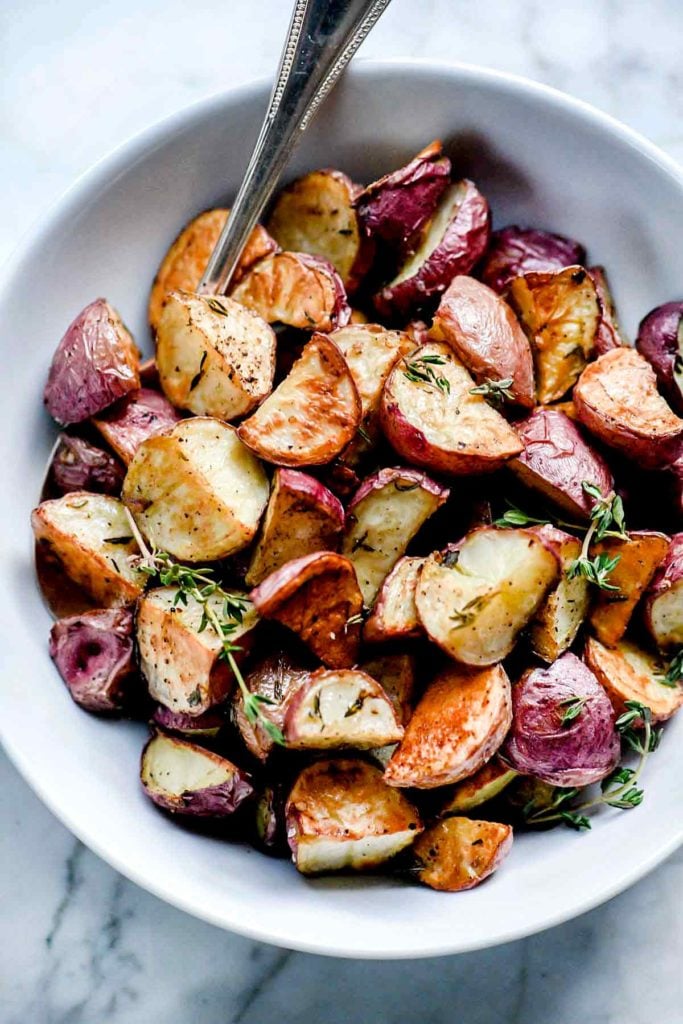 crispy roasted potatoes in white bowl with spoon