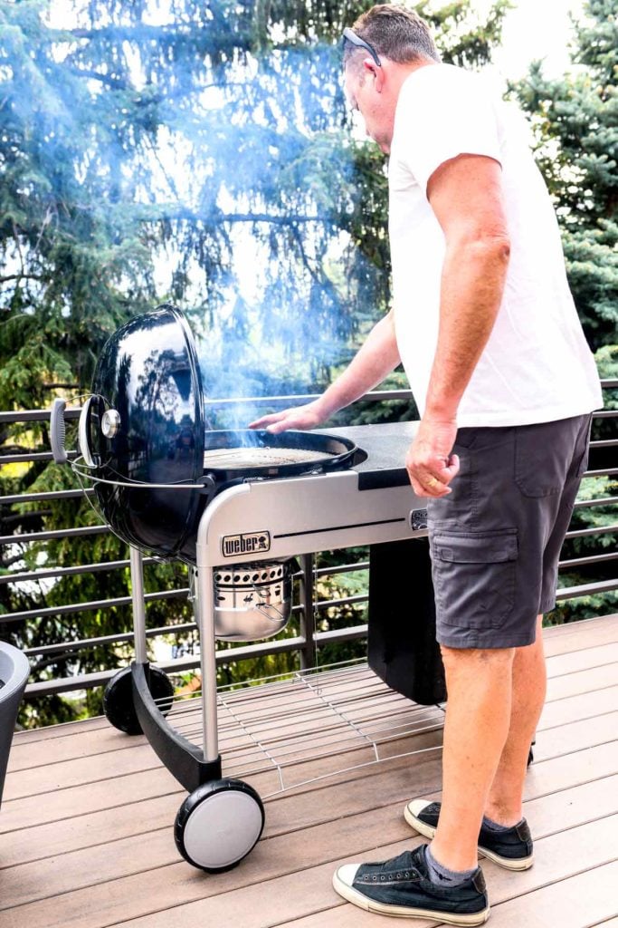 A man holding his hand above a charcoal grill to test its temperature