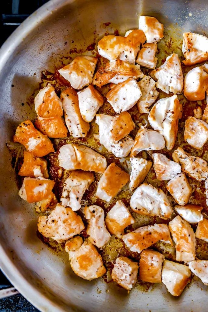 Diced chicken browning in a skillet 