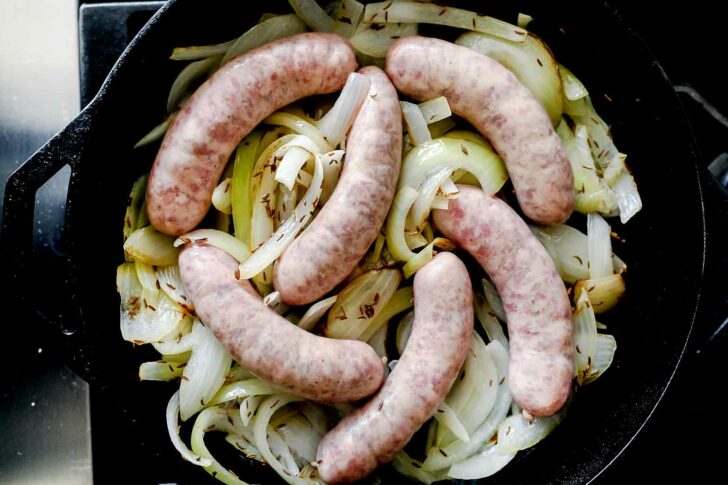 bratwurst in onions in pan | foodiecrush.com 