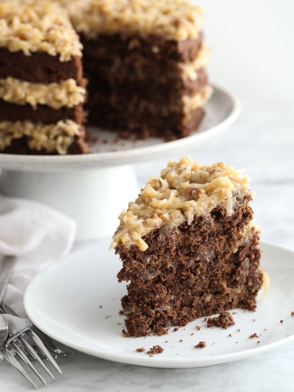 slice of homemade german chocolate cake on plate in front of cake stand