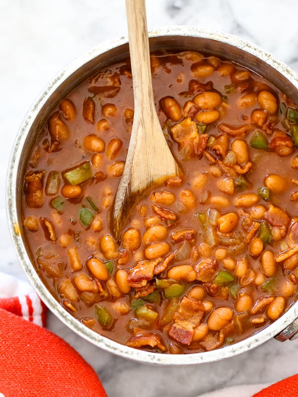 bbq baked beans in dutch oven with wooden spoon