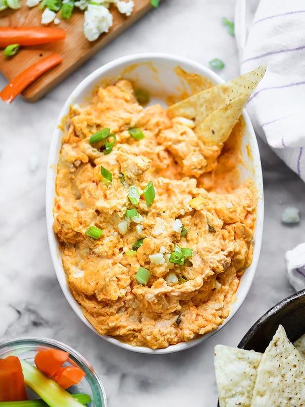 crockpot buffalo chicken dip in white serving dish with tortilla chip
