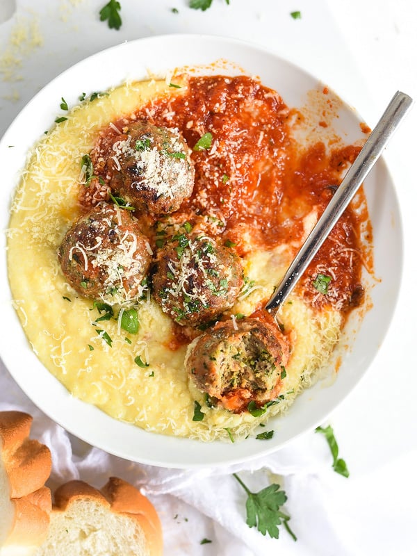 Baked Turkey Meatballs with Polenta and Marinara in white bowl with spoon