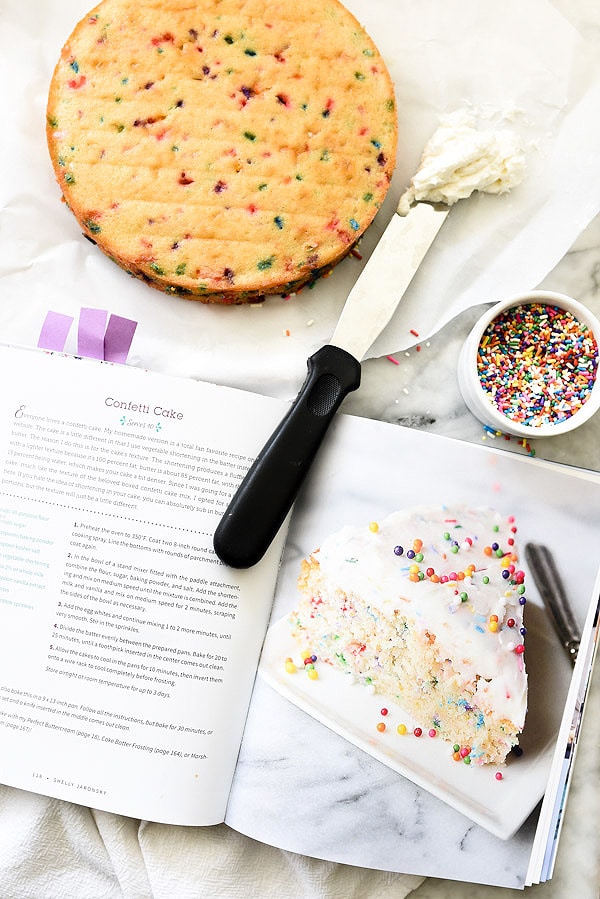 unfrosted confetti cake layer next to open cookbook