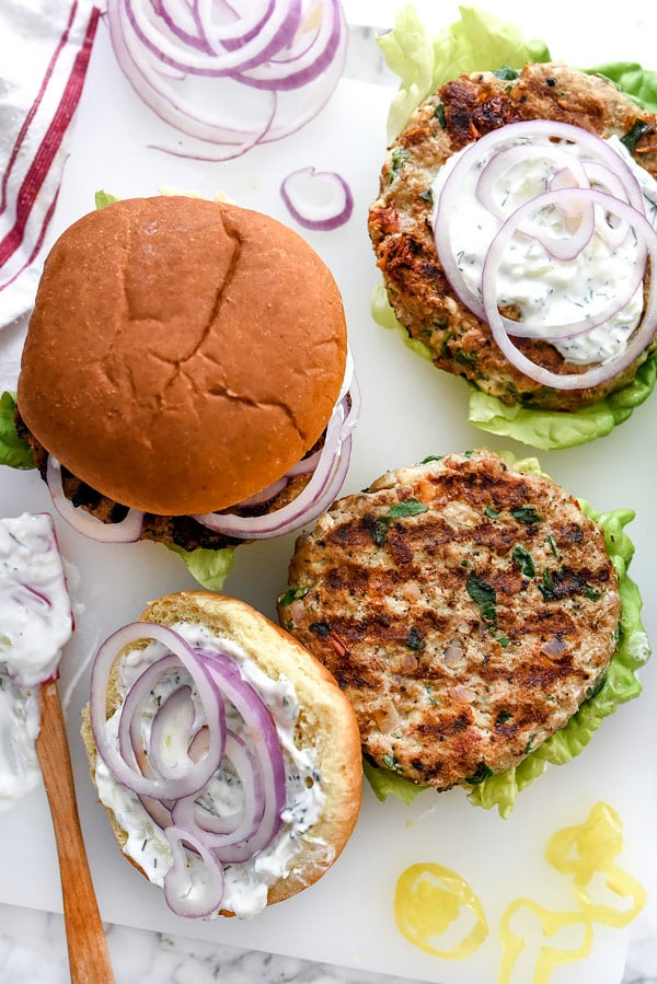 Greek Turkey Burgers with Tzatziki Sauce are packed with fresh spinach, sun-dried tomatoes, oregano and feta cheese for a healthy Mediterranean version for hamburger fans | foodiecrush.com