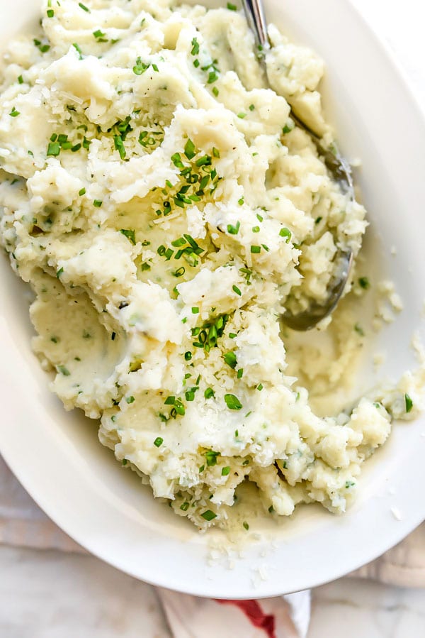 Mashed Cauliflower with Parmesan and chives in white serving dish