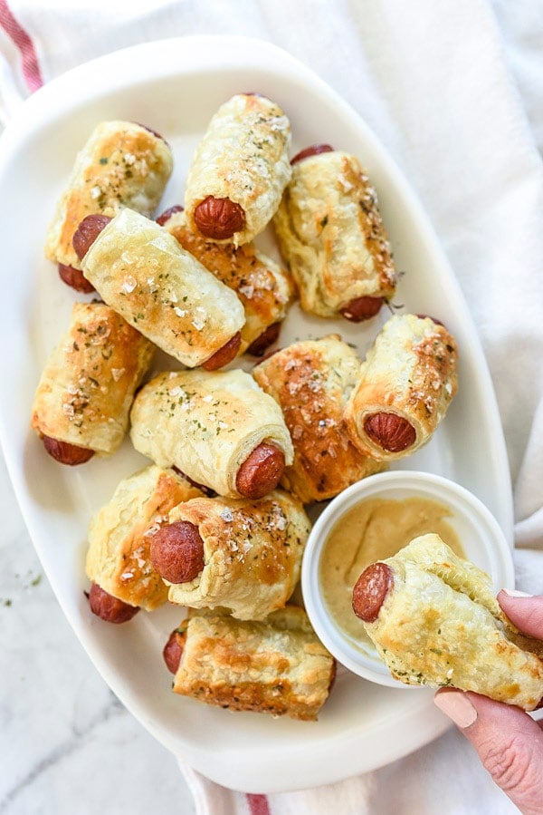 pigs in a blanket on white platter with mustard