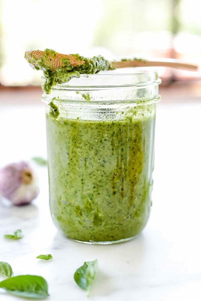 basil pesto in jar with wooden spoon resting on top