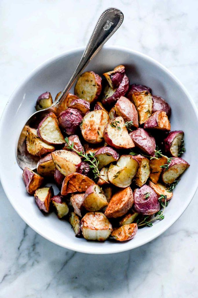 oven roasted potatoes in white serving bowl with spoon