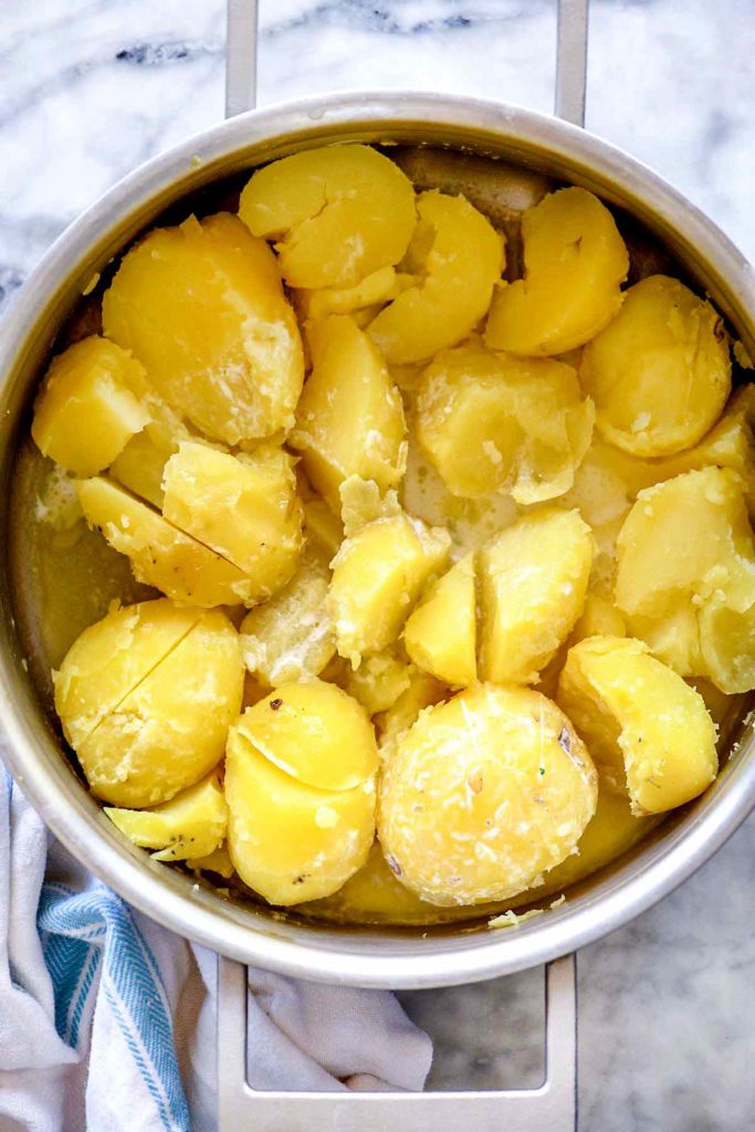 Potatoes with butter and half and half in a pot for creamy mashed potatoes