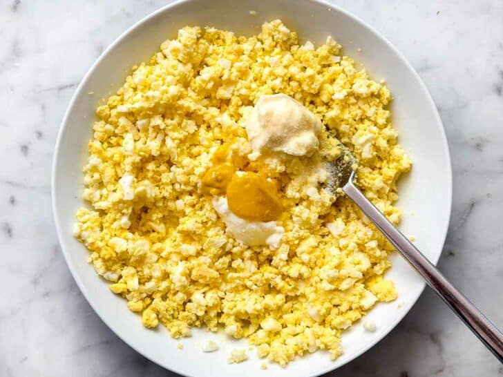Eggs mashed in bowl with mayonnaise and mustard for egg salad foodiecrush.com