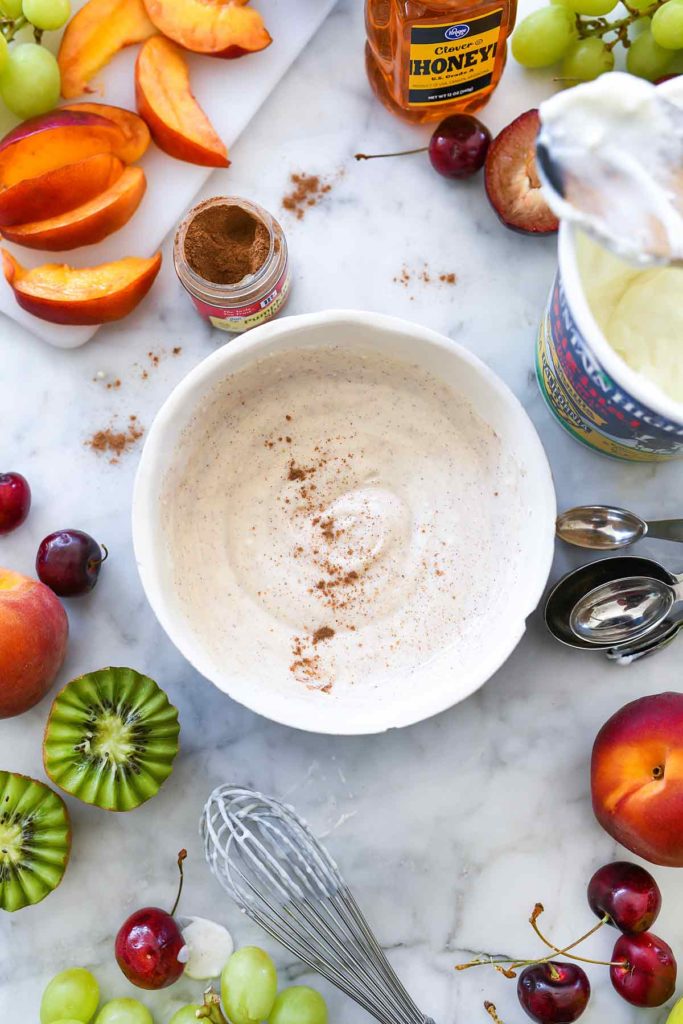 bowl of healthy fruit dip surrounded by fresh fruit and spices