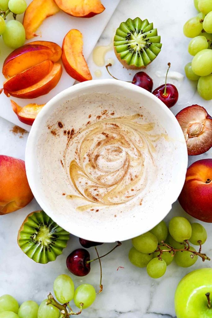 yogurt fruit dip in white bowl surrounded by fresh fruit