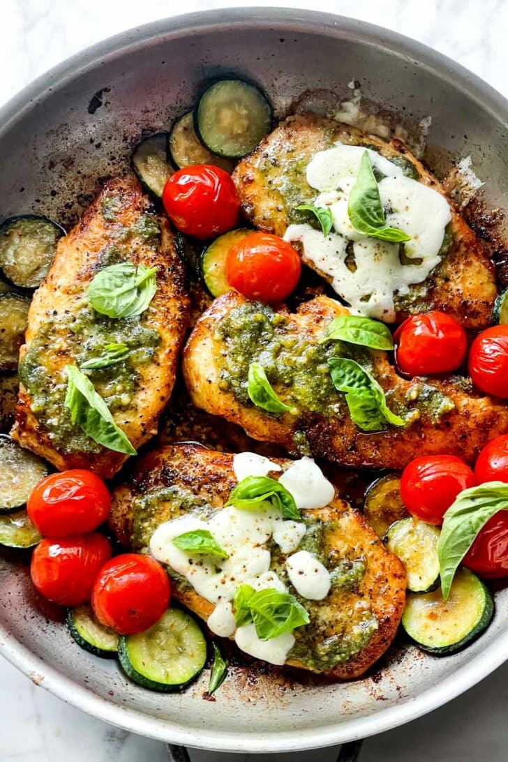 Pesto Chicken Recipe in skillet with tomatoes and zucchini foodiecrush.com