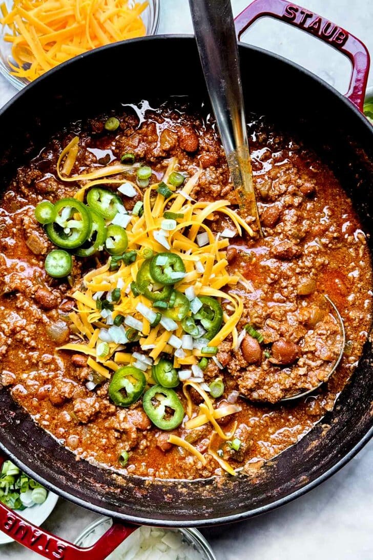 The Best Beef Chili Recipe with ground beef and beans and cheese and jalapenos in stockpot with ladle foodiecrush.com