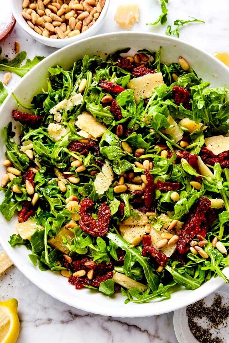 Arugula Salad with Sun Dried Tomatoes, Parmesan, and Pine Nuts Salad in bowl with fork foodiecrush.com #arugulasalad