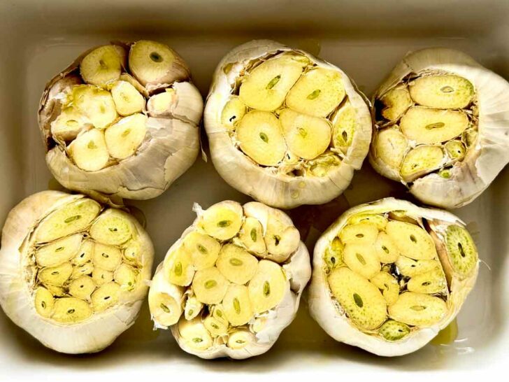 Garlic bulbs for roasted garlic drizzled with olive oil in baking dish foodiecrush.com #roastedgarlic