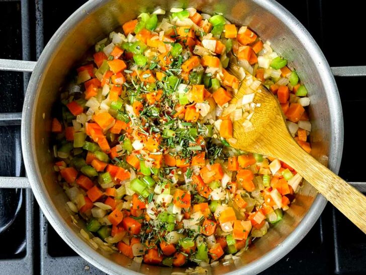 Carrots celery onion garlic rosemary in pot with spoon trilogy foodiecrush.com