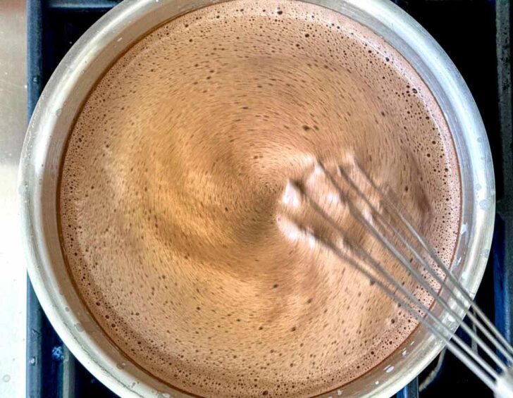 Hot chocolate ingredients in pan with whisk Hot Chocolate with whipped cream and marshmallows foodiecrush.com #recipe #hotchocolate homemade