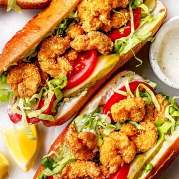 Three Shrimp Po Boys with tomato and lettuce and pickles