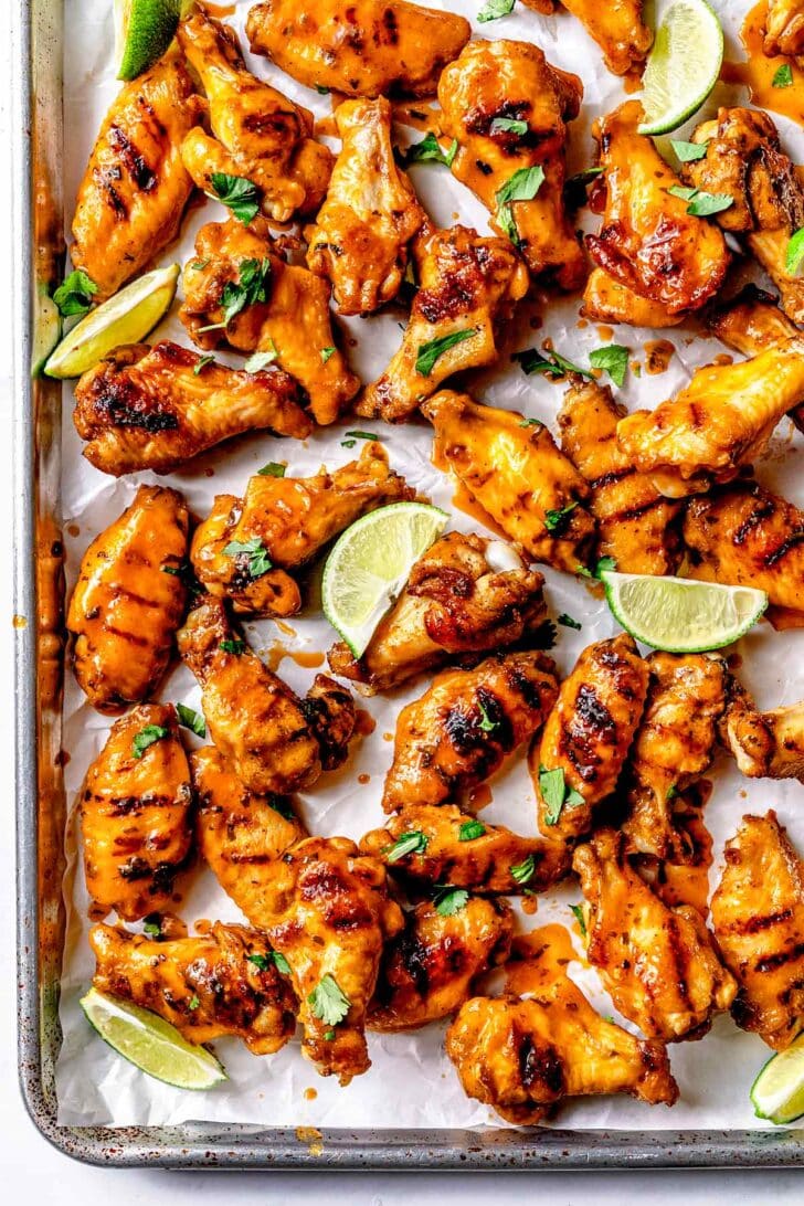 Honey Sriracha Chicken Wings recipe with lime wedges on baking sheet