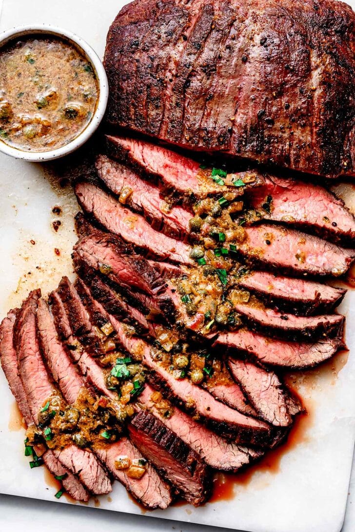 Pan-Seared Flank Steak with Mustard Caper Sauce on cutting board