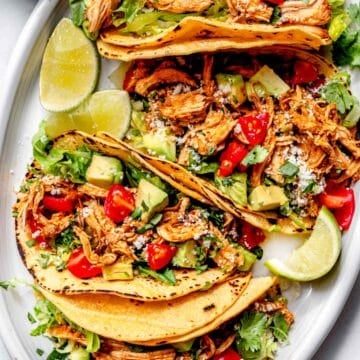 Shredded Chicken Tacos on platter with limes