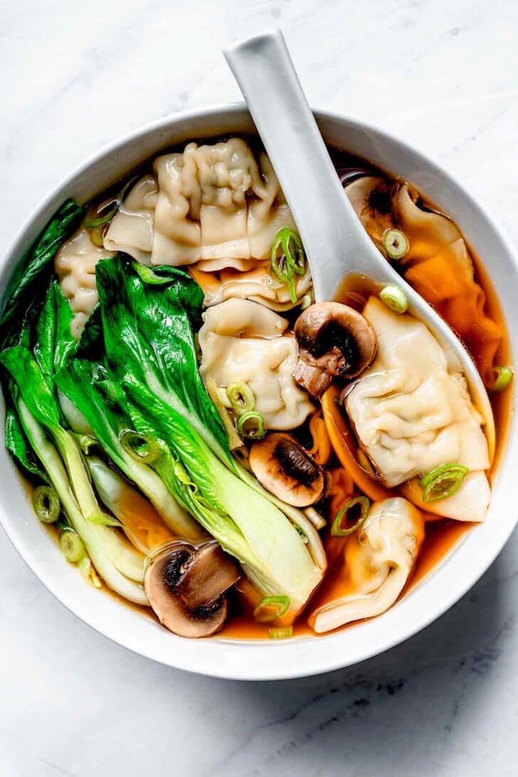 Wonton Soup with mushrooms and bok choy in bowl with spoon