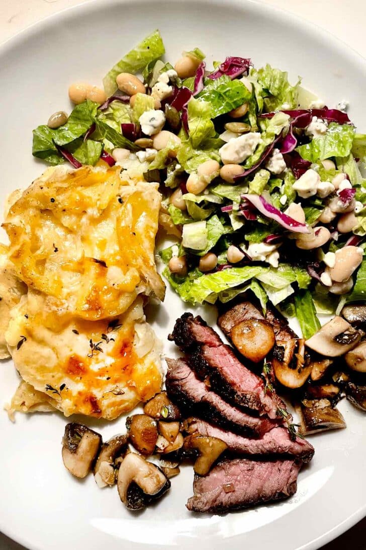 Steak, salad, and au gratin potatoes on plate