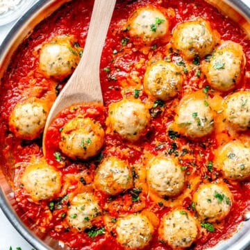 Marinara cooking in skillet next to Chicken Meatballs Parmesan in marinara in skillet