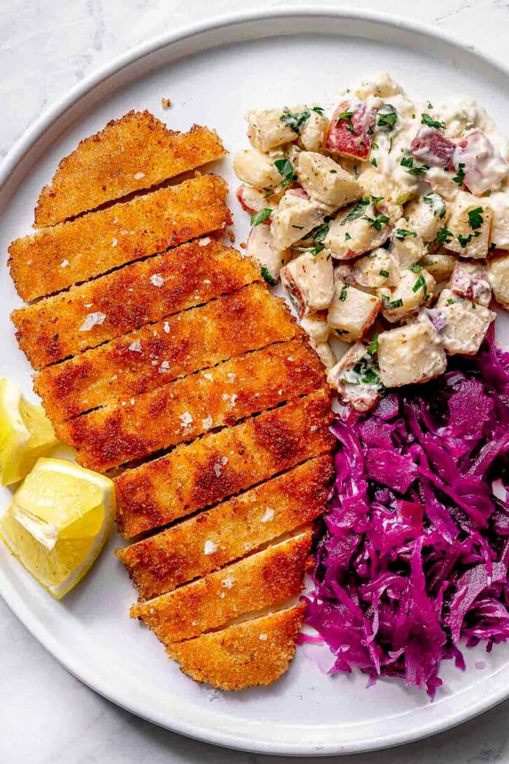 Chicken Schnitzel on plate with potato salad and sweet and sour red cabbage