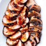 Grilled Asian Pork Tenderloin recipe with sauce on serving platter