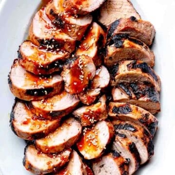 Grilled Asian Pork Tenderloin recipe with sauce on serving platter