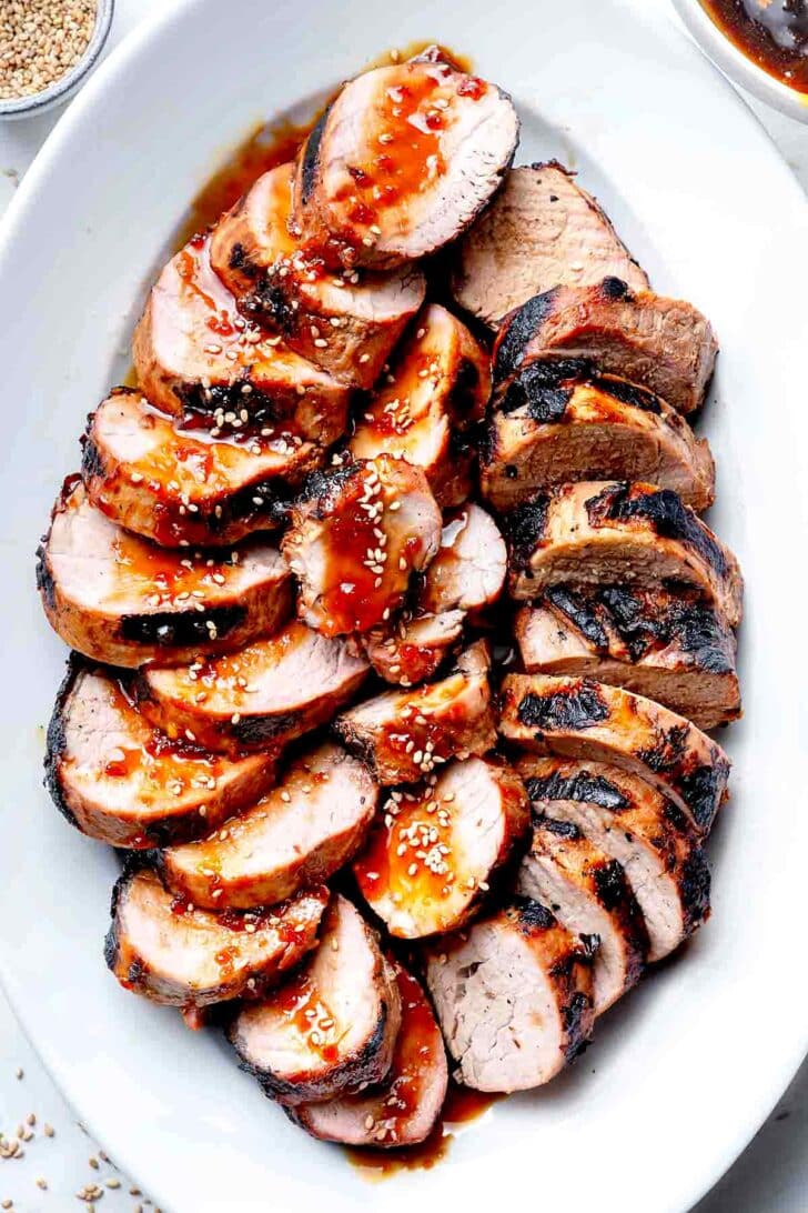 Grilled Asian Pork Tenderloin recipe with sauce on serving platter