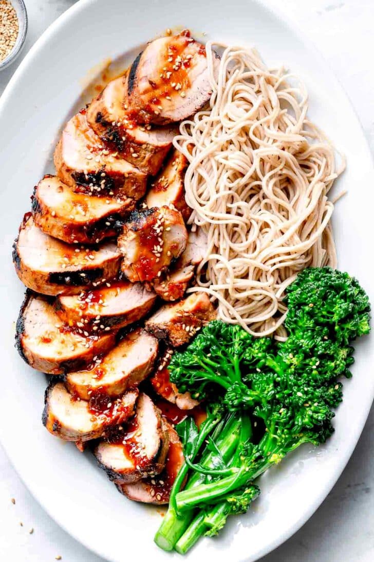 Asian Pork Tenderloin with noodles and broccoli on platter